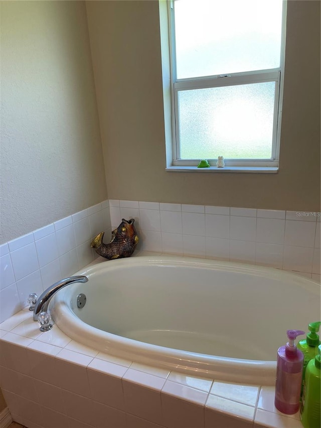 bathroom featuring plenty of natural light and tiled tub