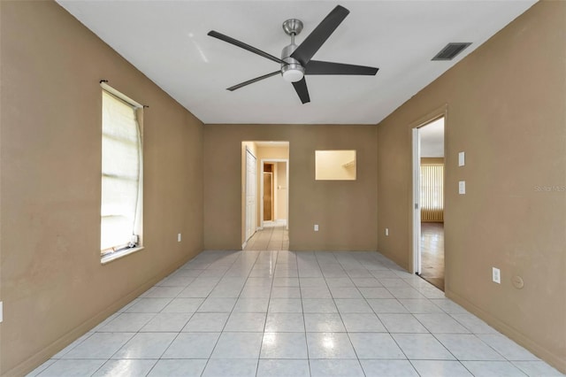 spare room featuring ceiling fan, light tile patterned flooring, and a healthy amount of sunlight