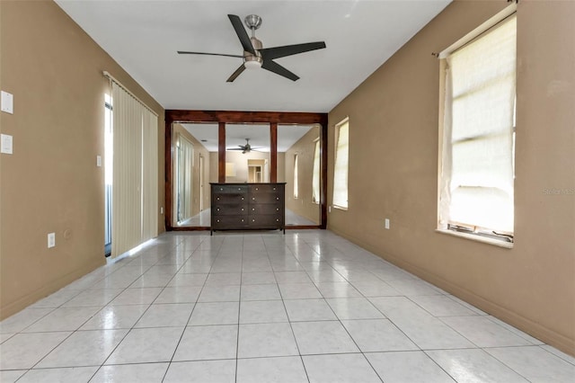 unfurnished living room with light tile patterned floors, beamed ceiling, ceiling fan, and plenty of natural light