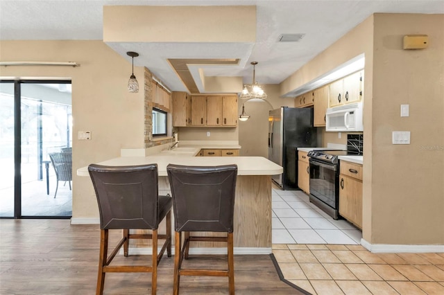 kitchen featuring pendant lighting, electric range, kitchen peninsula, a kitchen bar, and stainless steel fridge