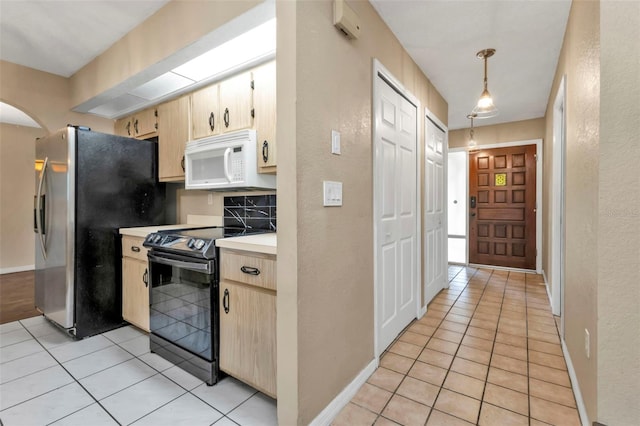 kitchen with pendant lighting, light tile patterned floors, black electric range oven, and stainless steel fridge