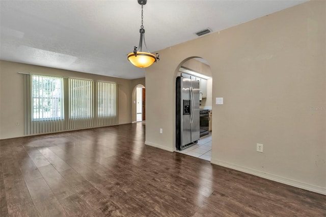 empty room with light wood-type flooring and a textured ceiling