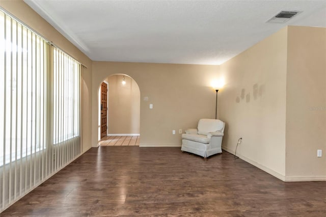 unfurnished room featuring a textured ceiling, plenty of natural light, and dark hardwood / wood-style flooring