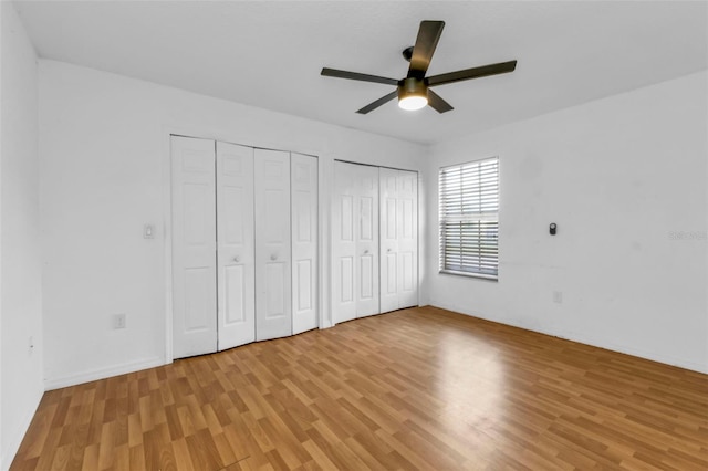 unfurnished bedroom with ceiling fan, multiple closets, and light hardwood / wood-style flooring