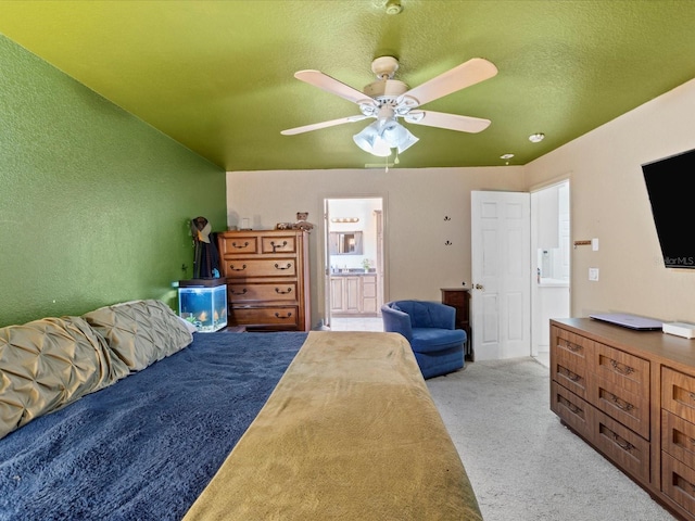 bedroom featuring a textured ceiling, light colored carpet, ceiling fan, and ensuite bathroom