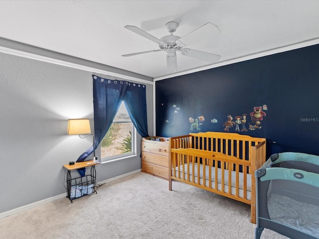 bedroom with a nursery area, carpet, and ceiling fan