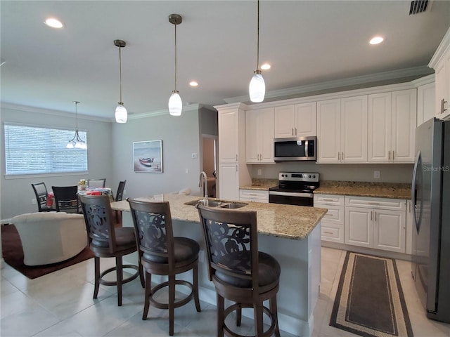 kitchen featuring appliances with stainless steel finishes, light stone counters, white cabinetry, sink, and an island with sink