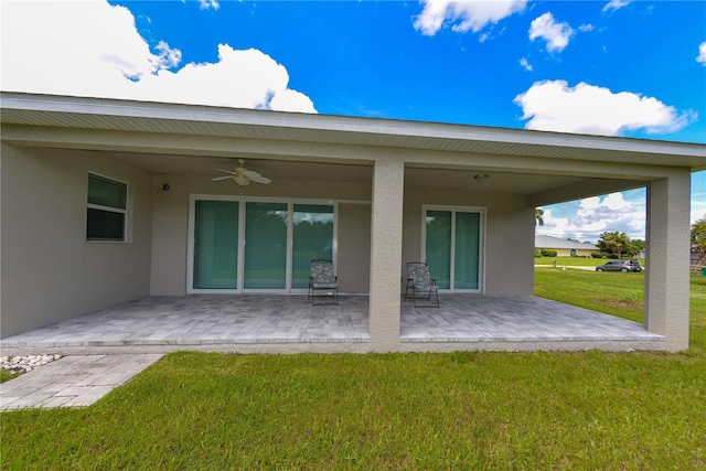 rear view of property with ceiling fan, a yard, and a patio