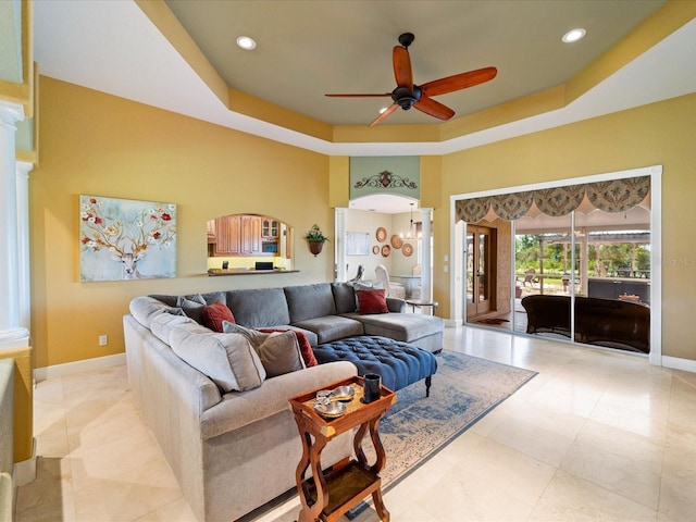 living room featuring ceiling fan and a raised ceiling