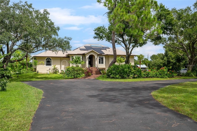 view of front facade featuring a front yard and solar panels