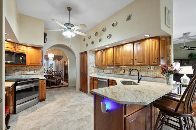 kitchen with sink, kitchen peninsula, a towering ceiling, appliances with stainless steel finishes, and ceiling fan