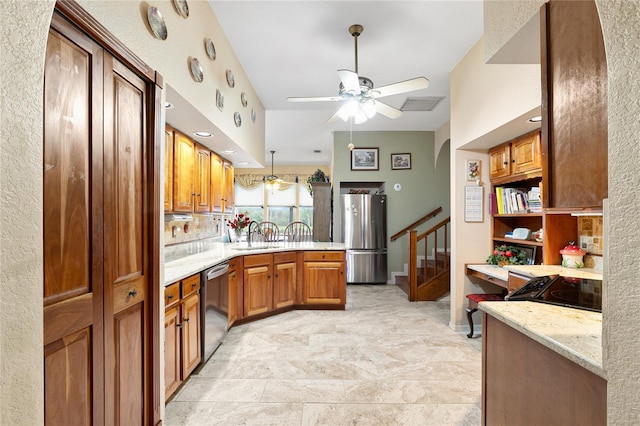 kitchen featuring kitchen peninsula, light stone countertops, stainless steel appliances, ceiling fan, and sink