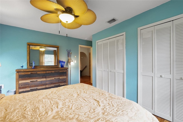 bedroom with hardwood / wood-style floors, ceiling fan, and multiple closets