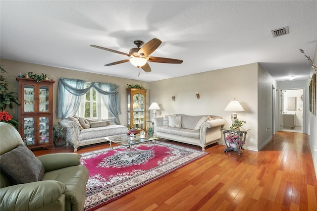 living room with ceiling fan, hardwood / wood-style floors, and a textured ceiling