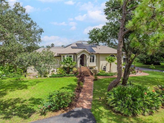 view of front of home with a front lawn and solar panels