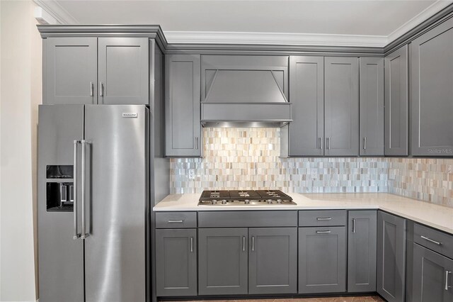 kitchen featuring appliances with stainless steel finishes, custom range hood, gray cabinetry, and decorative backsplash