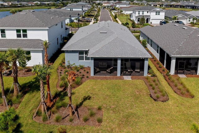 rear view of property featuring a sunroom and a lawn