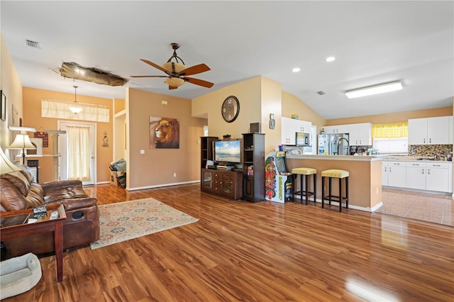 living room with lofted ceiling, ceiling fan, sink, and light tile patterned flooring