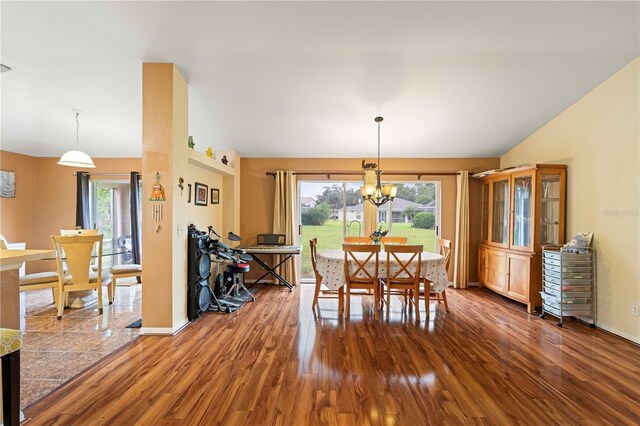 dining room with dark wood-type flooring, vaulted ceiling, and a notable chandelier