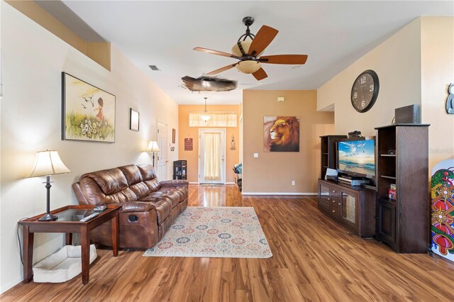 living room with baseboards, wood finished floors, visible vents, and a ceiling fan