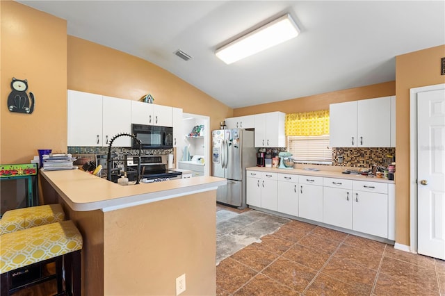 kitchen featuring tile patterned floors, stainless steel appliances, tasteful backsplash, and vaulted ceiling