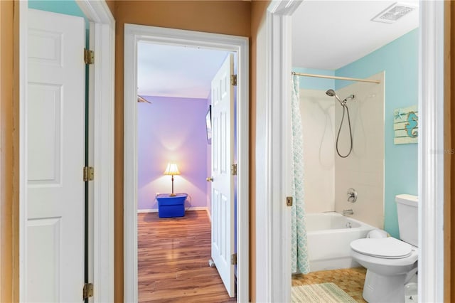 bathroom with toilet, hardwood / wood-style flooring, and shower / tub combo with curtain