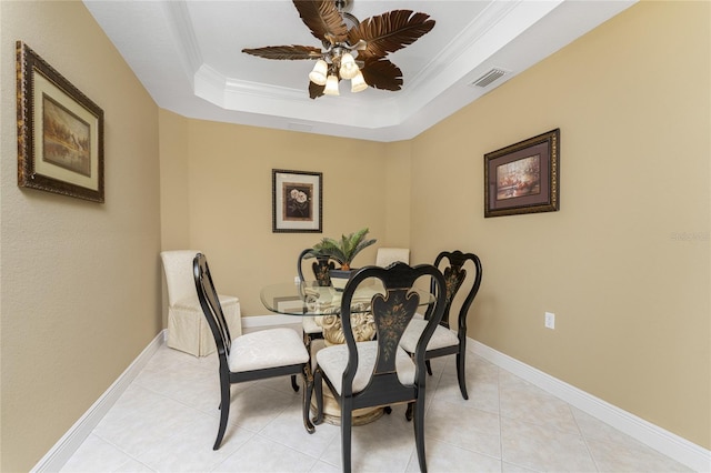 tiled dining area featuring crown molding, ceiling fan, and a raised ceiling