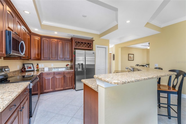 kitchen with a kitchen bar, stainless steel appliances, ornamental molding, ceiling fan, and light stone counters