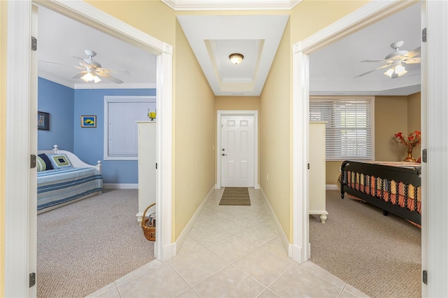 carpeted entrance foyer with ceiling fan, a raised ceiling, and ornamental molding