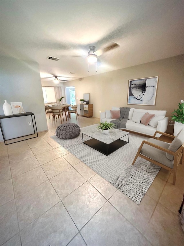 living room with visible vents, light tile patterned flooring, and a ceiling fan