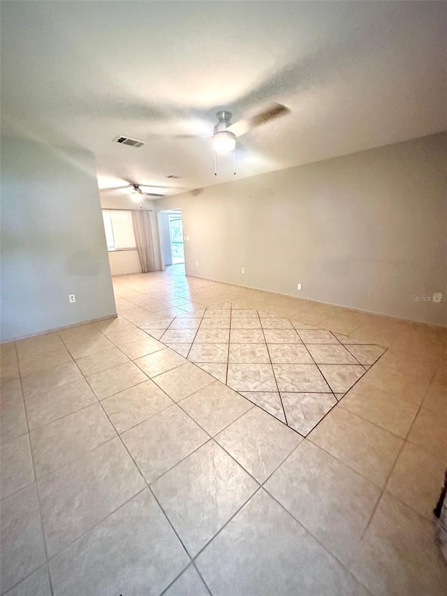 empty room with light tile patterned floors and a ceiling fan