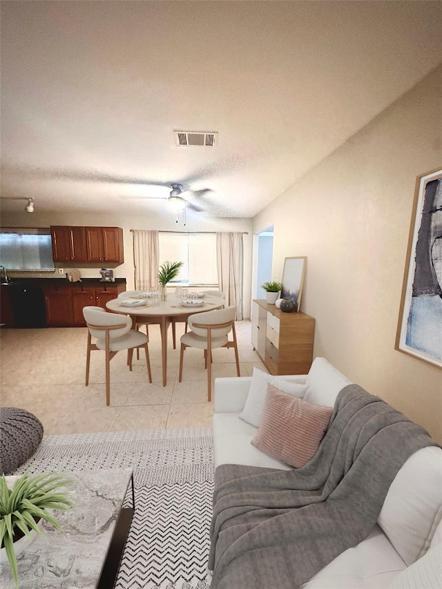 tiled living room with a textured ceiling, ceiling fan, and lofted ceiling