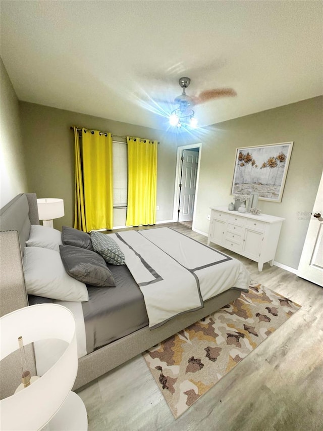 bedroom with baseboards, light wood-type flooring, and a ceiling fan