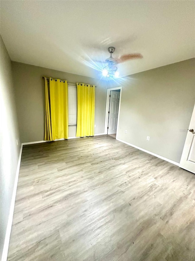 unfurnished room featuring baseboards, wood finished floors, and a ceiling fan