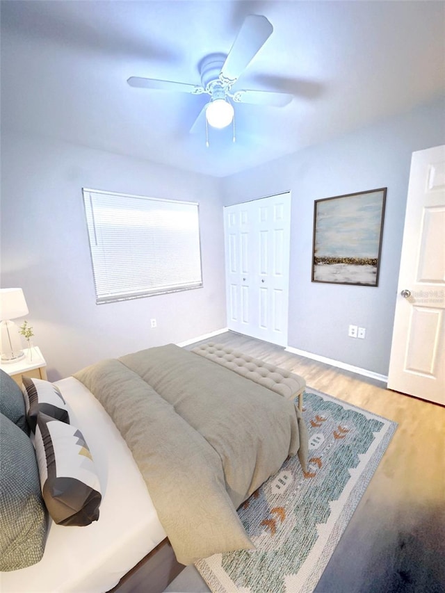 bedroom featuring a closet, baseboards, a ceiling fan, and wood finished floors