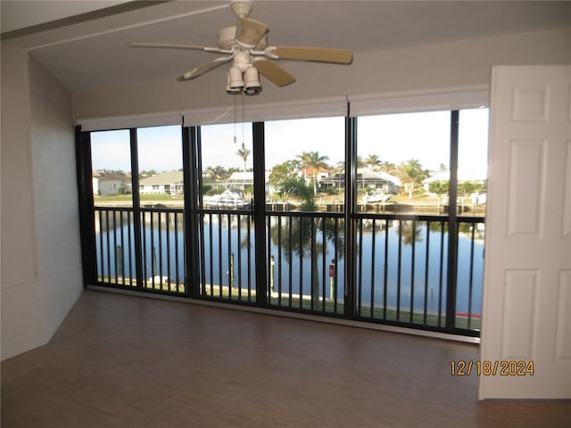 unfurnished sunroom with ceiling fan, plenty of natural light, and a water view