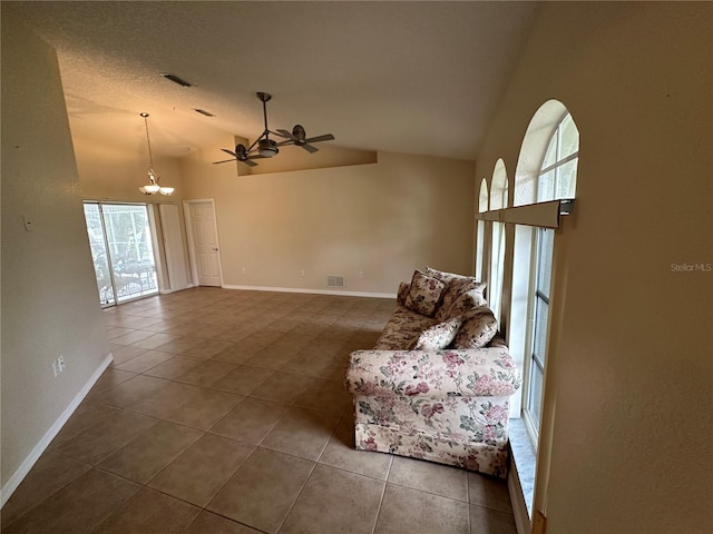 unfurnished living room featuring ceiling fan with notable chandelier, dark tile patterned flooring, high vaulted ceiling, and a wealth of natural light