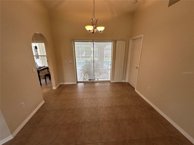 tiled spare room with an inviting chandelier