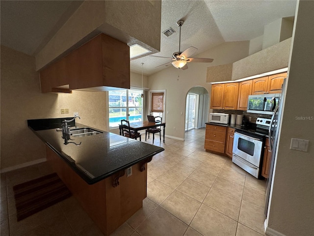 kitchen with light tile patterned floors, stainless steel appliances, kitchen peninsula, sink, and ceiling fan