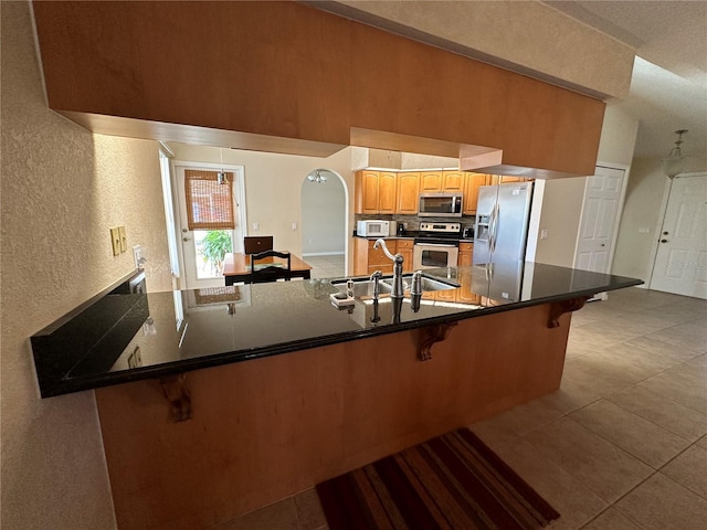 kitchen with appliances with stainless steel finishes, a kitchen breakfast bar, kitchen peninsula, and sink