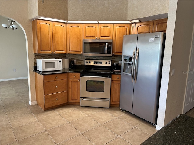 kitchen featuring appliances with stainless steel finishes, light tile patterned floors, and backsplash