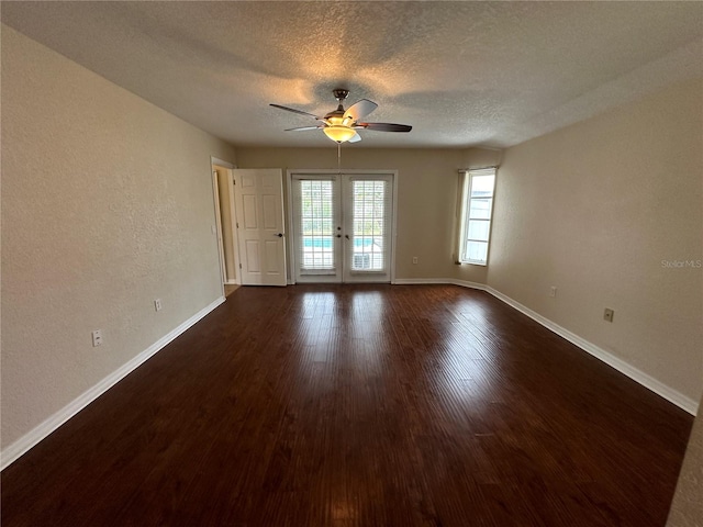 empty room featuring ceiling fan, dark hardwood / wood-style floors, a textured ceiling, and french doors