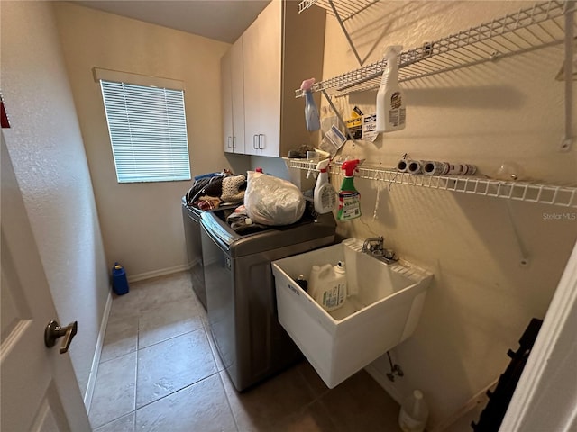 clothes washing area with washing machine and clothes dryer, cabinets, sink, and tile patterned floors