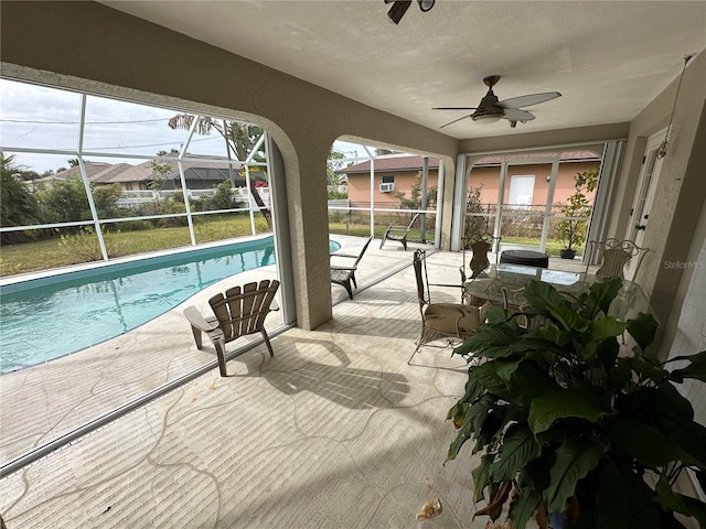 view of pool featuring glass enclosure, ceiling fan, and a patio area