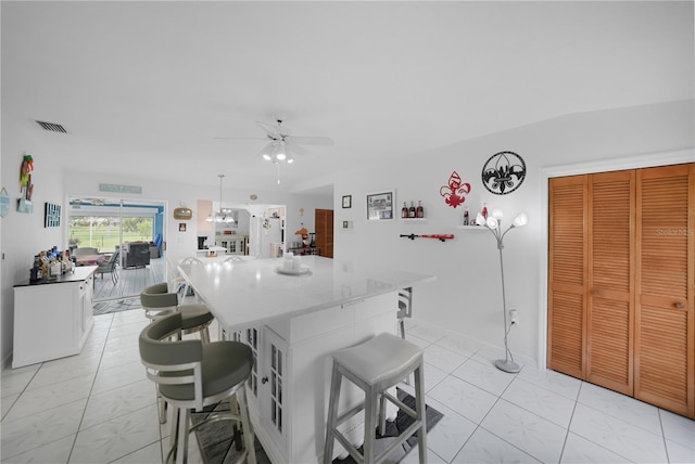 kitchen featuring a kitchen island, ceiling fan, white cabinets, and a breakfast bar area