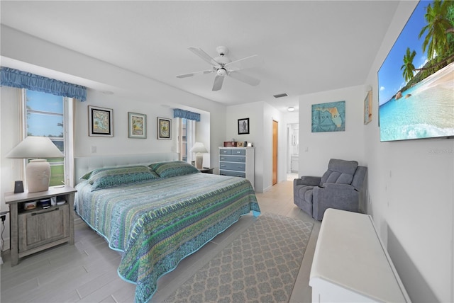 bedroom featuring light hardwood / wood-style flooring, ceiling fan, and connected bathroom