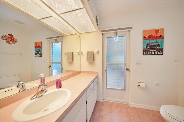 bathroom with vanity, toilet, a wealth of natural light, and tile patterned flooring