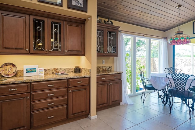 kitchen featuring wood ceiling, light stone counters, light tile patterned flooring, and pendant lighting