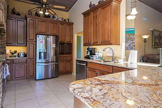 kitchen featuring stainless steel appliances, a ceiling fan, light tile patterned flooring, a sink, and light stone countertops