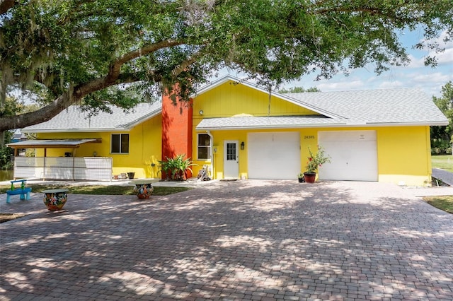 ranch-style house featuring a garage, decorative driveway, a shingled roof, and stucco siding